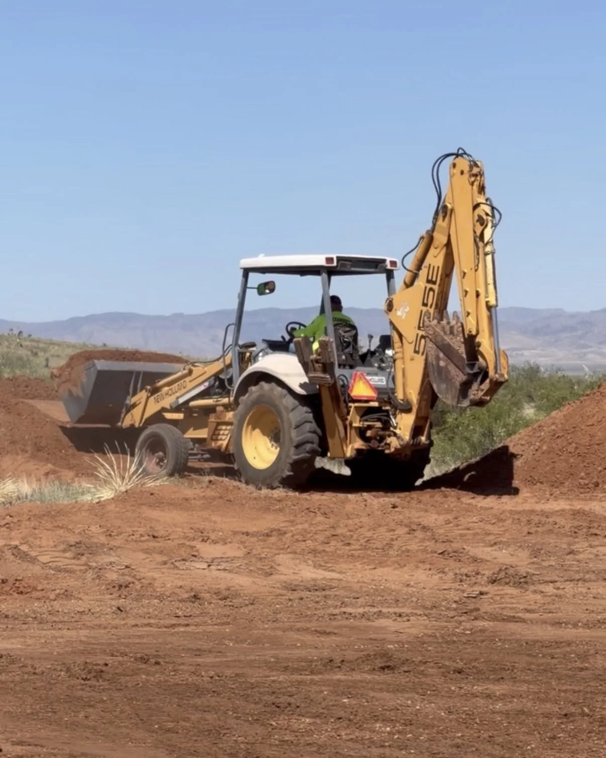 Backhoe working on red desert soil