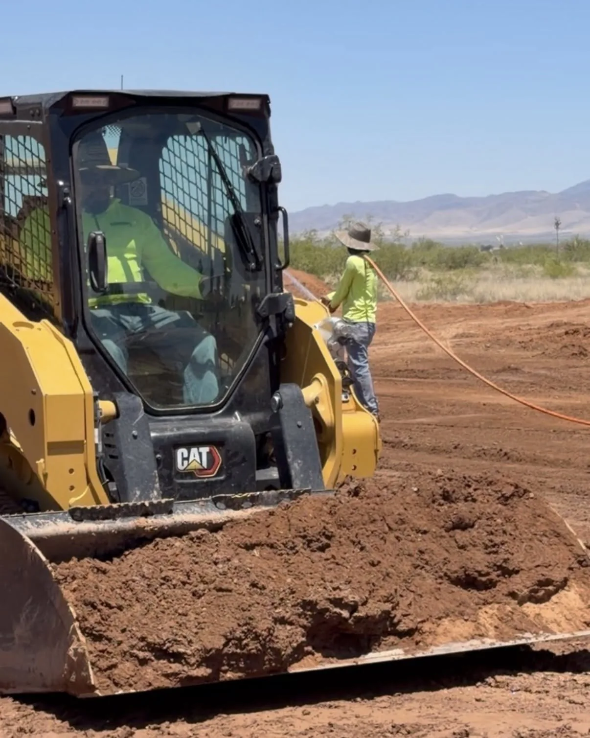 CAT skid steer and crew grading a construction lot