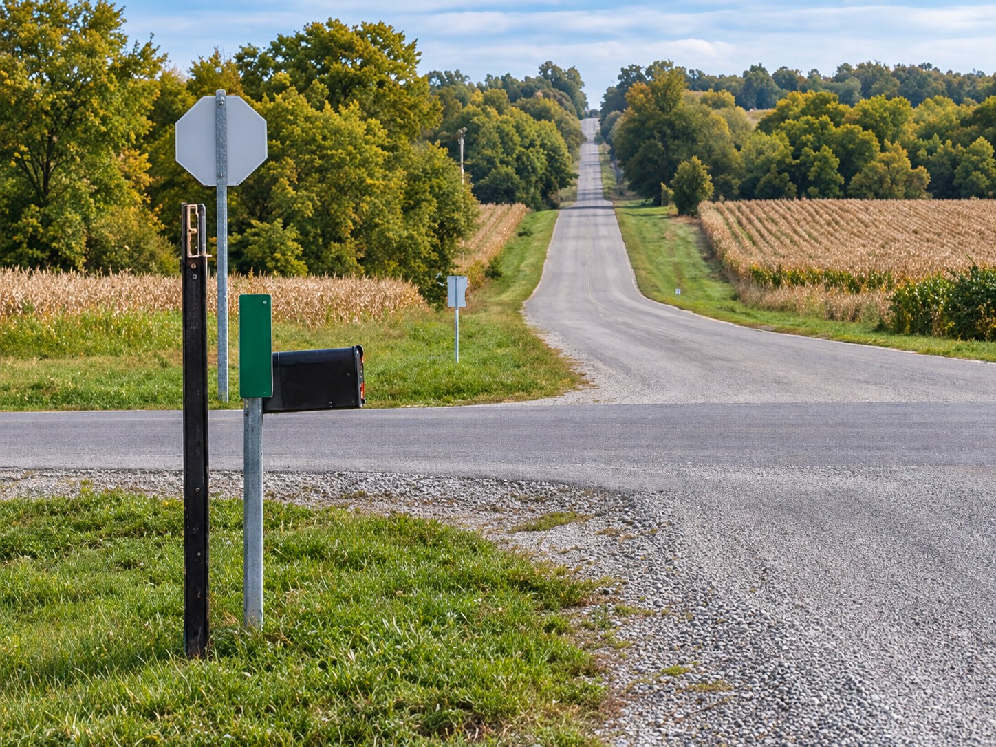 Road signs and an address marker at a rural intersection