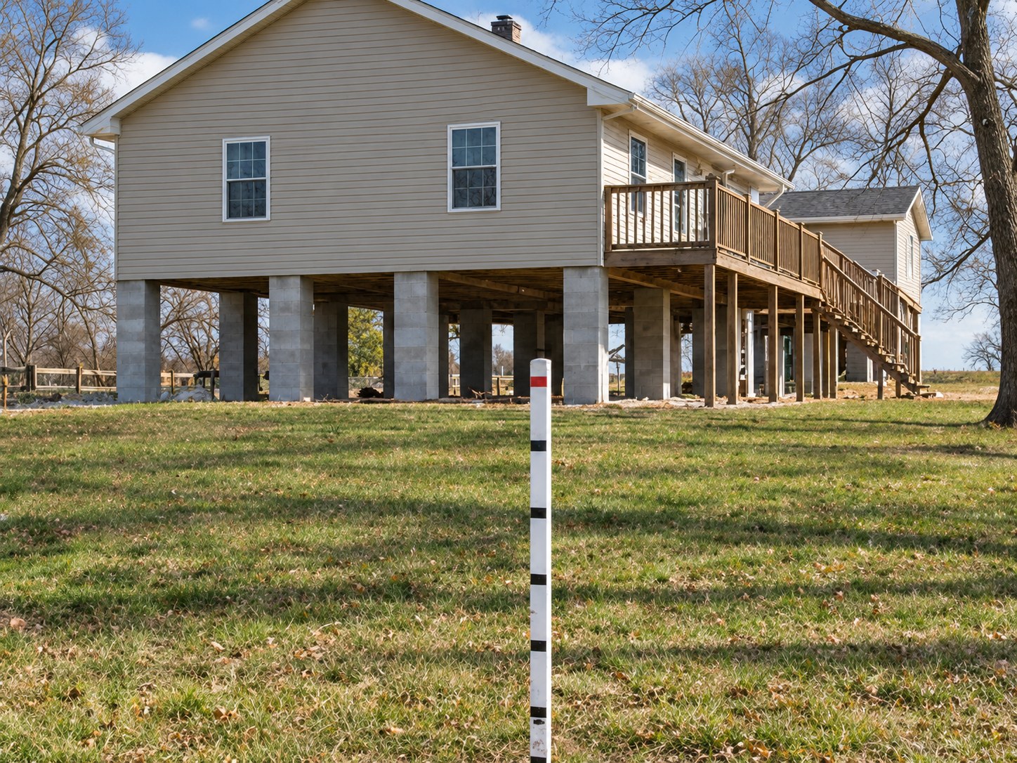 Elevated house beside a flood-level gauge