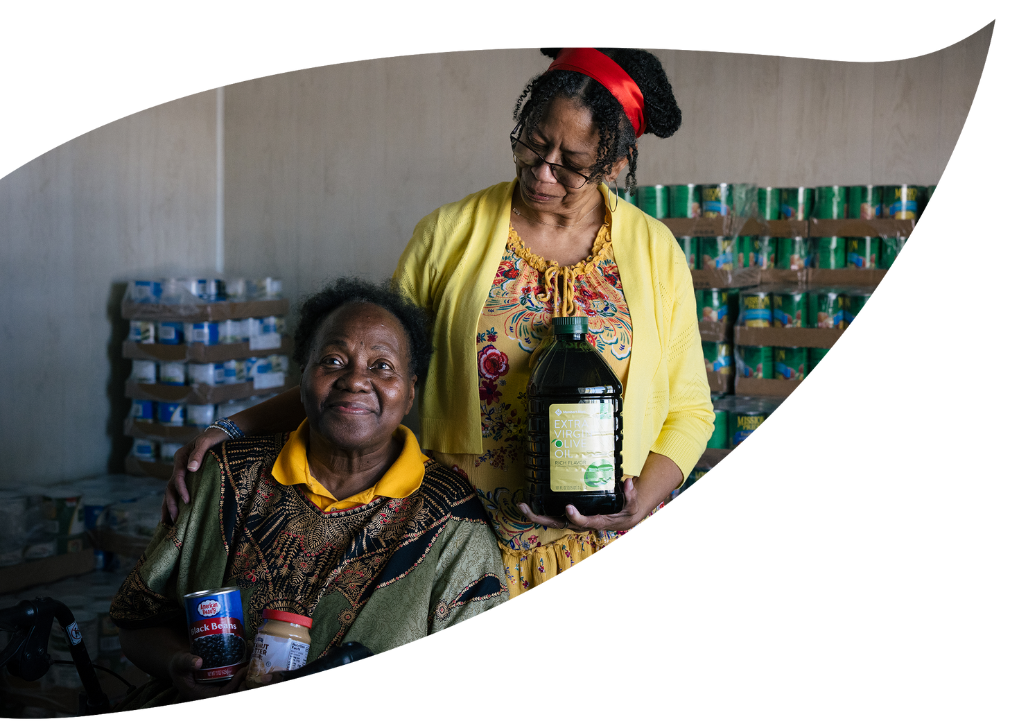 A volunteer handing groceries to a seated woman at a food pantry