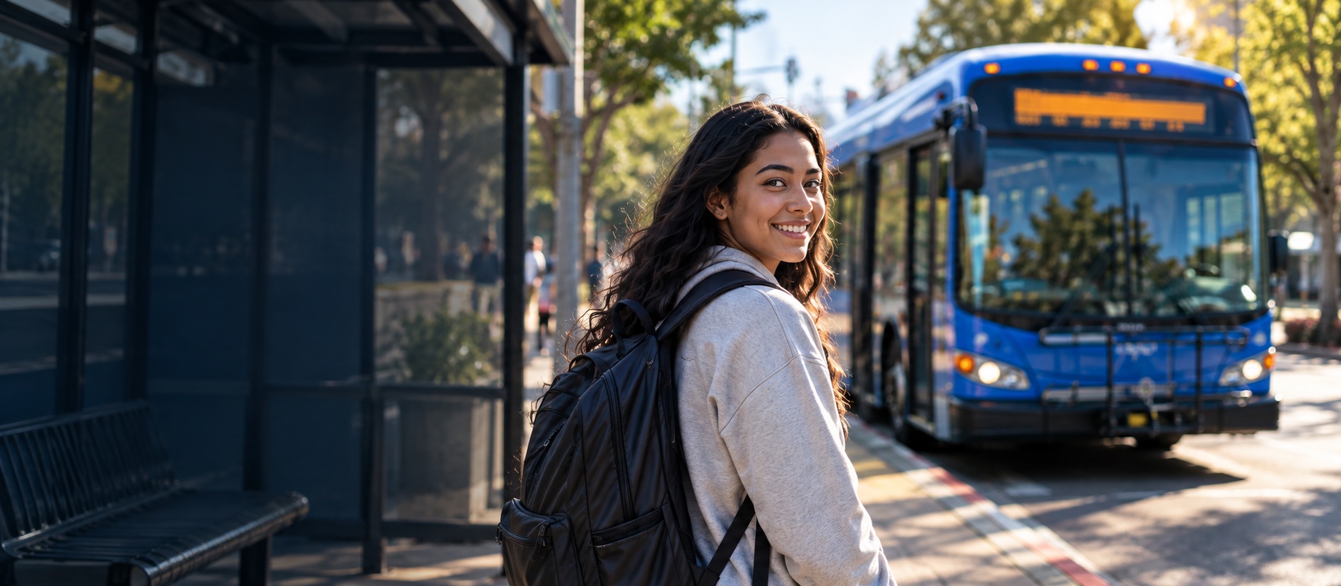 A student with a backpack smiling beside an AC Transit bus at a West County stop