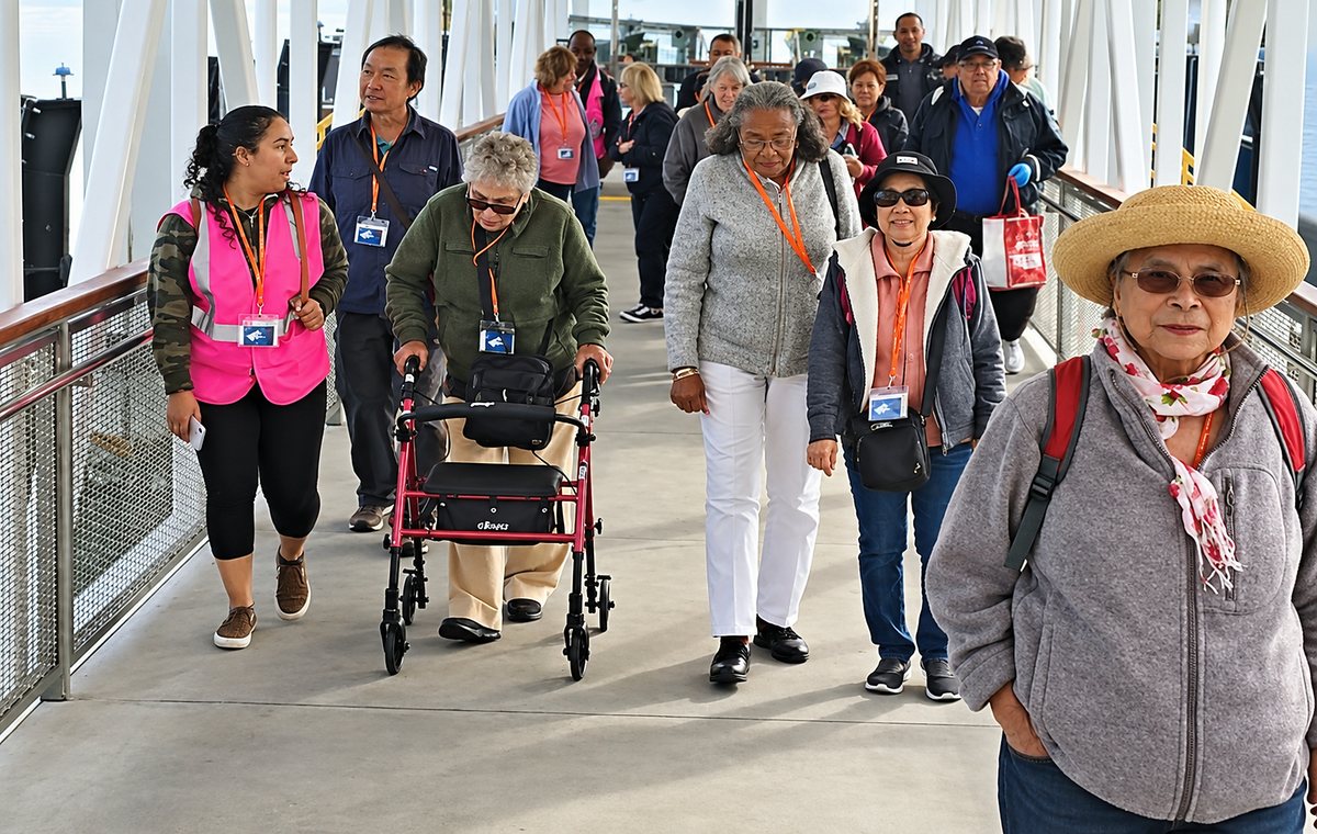 Riders including older adults and a person using a walker on a transit centre ramp