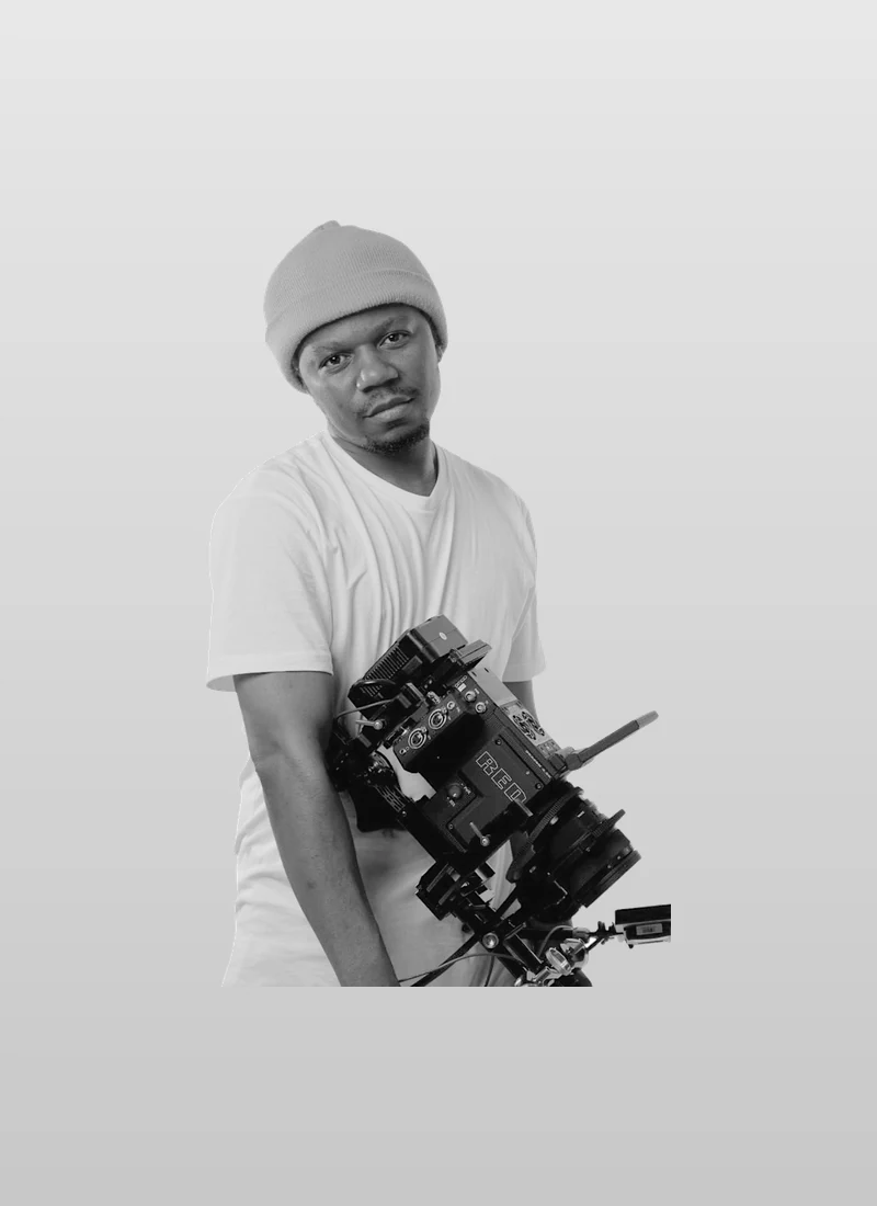 Prince Desire Magomo in a knit beanie, holding a cinema camera